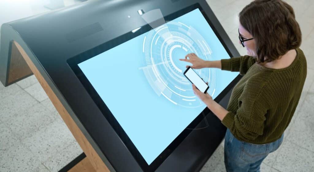 Woman using a self-service kiosk that depends on MDM lockdown, showing the risk when you cancel MDM