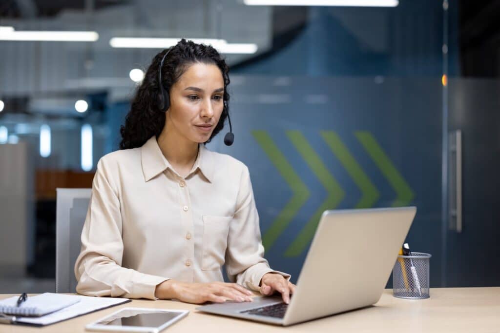 IT support specialist with a headset at her laptop, showing how MDM reduces IT tickets