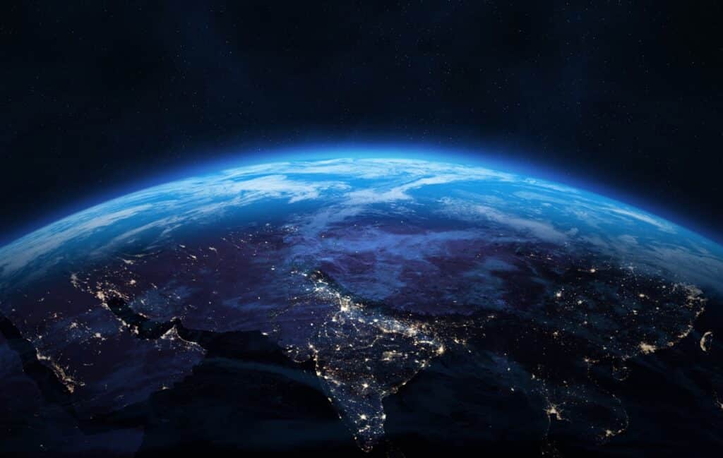 Earth at night with glowing city lights representing a global digital signage fleet management network