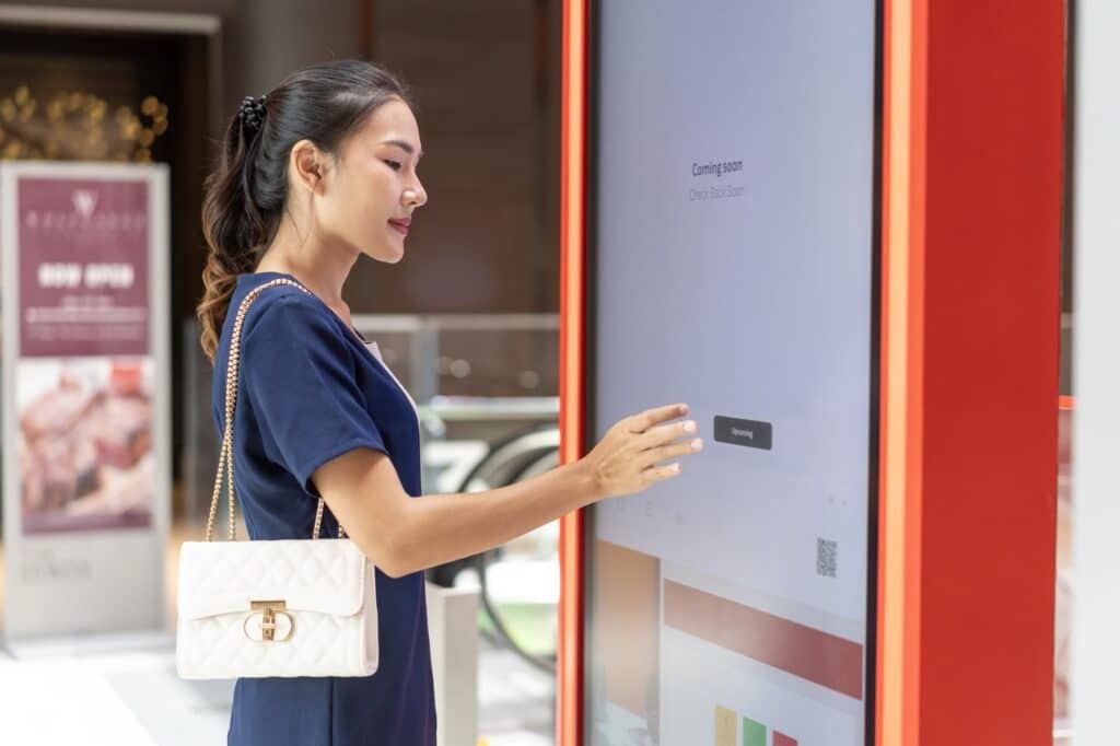 Shopper using an interactive information kiosk running multi-app kiosk mode in a mall